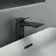 Schwarze Ideal Standard Armatur über einem weißen Waschbecken, mit geradem Auslauf und flacher Bedienoberfläche, montiert an einer hellen Wand.